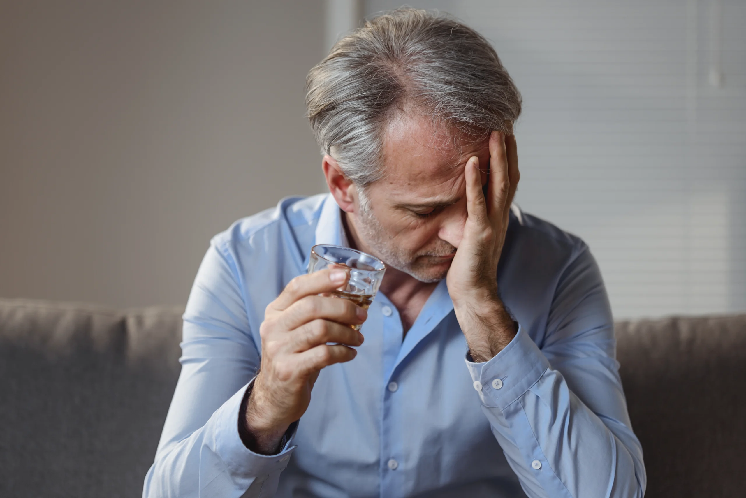 A man with a drink who is sad
