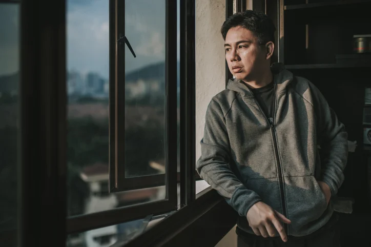 Adult man looking out a window contemplating