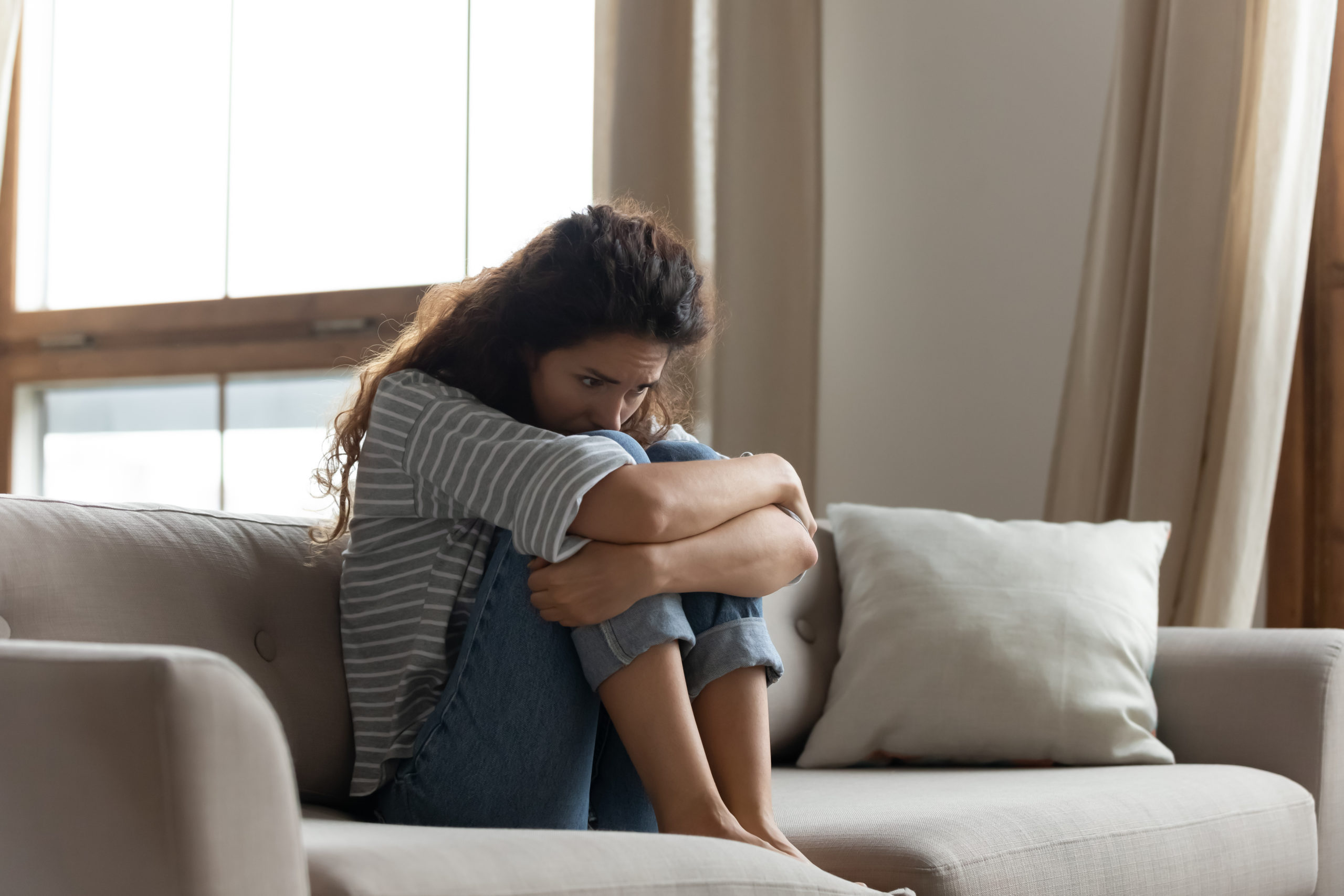 Sad woman hug knees sit on couch feels lonely goes through divorce or break up. Female with drug or alcohol addiction problem need rehab help. Unplanned pregnancy made decision about abortion