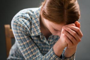 Woman hunched over with her hands on her forehead