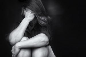 Black and white photo of a woman sitting down with her hand on her head, upset