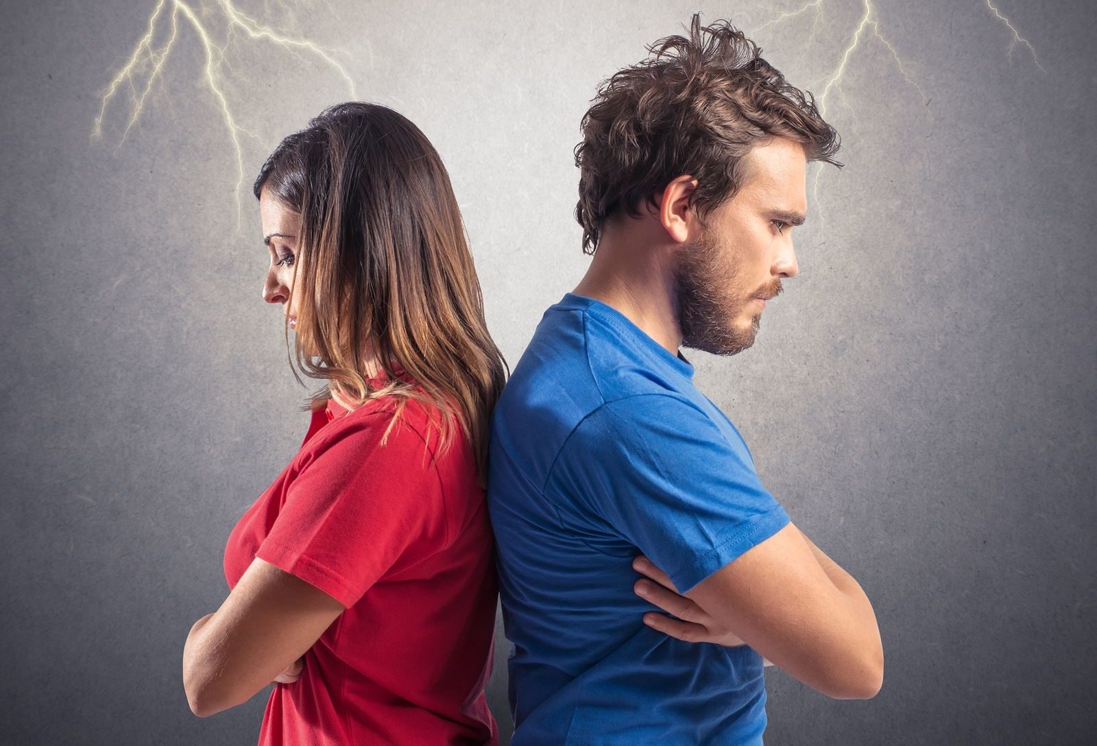 Distraught couple standing with their backs to each other and arms crossed