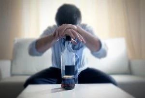 Drunk man leaning on a bottle of booze