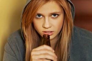 Teenage depressed woman sitting with beer bottle in her hand