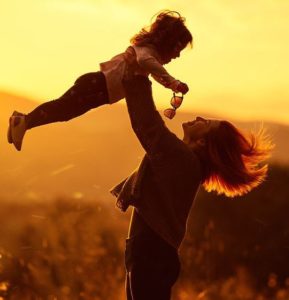 Mother playing with daughter, lifting her up in the air