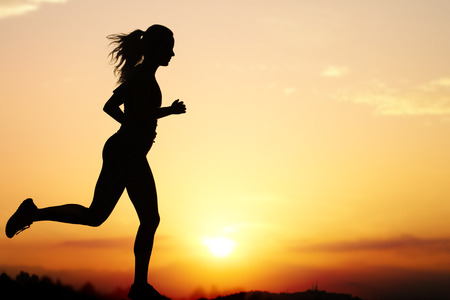 Silhouette of a woman jogging at sunset