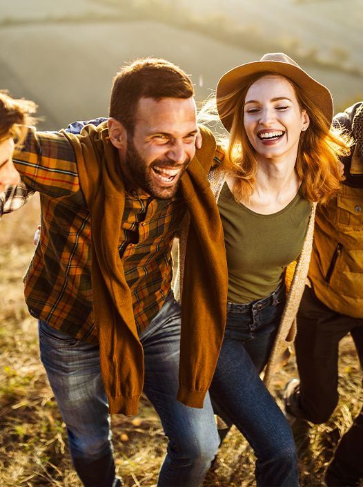 Group of friends standing around with their arms on each others shoulders smiling