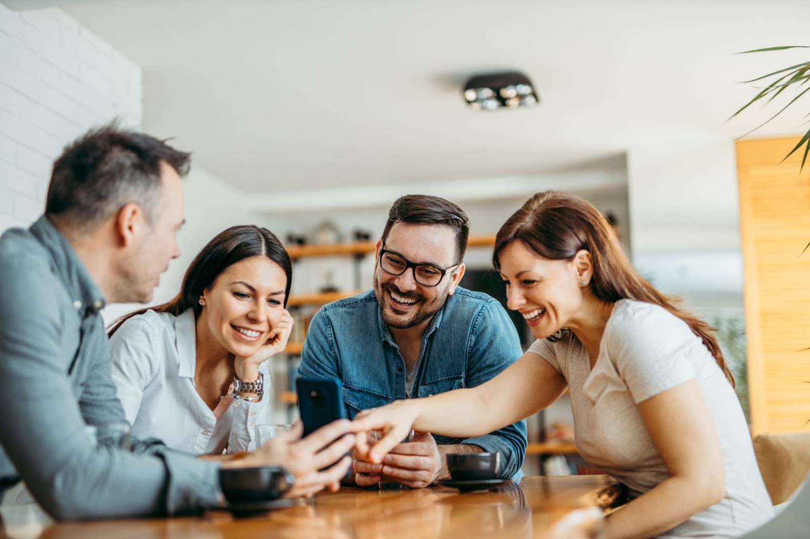 Group of friends sitting around a table looking at something on a phone