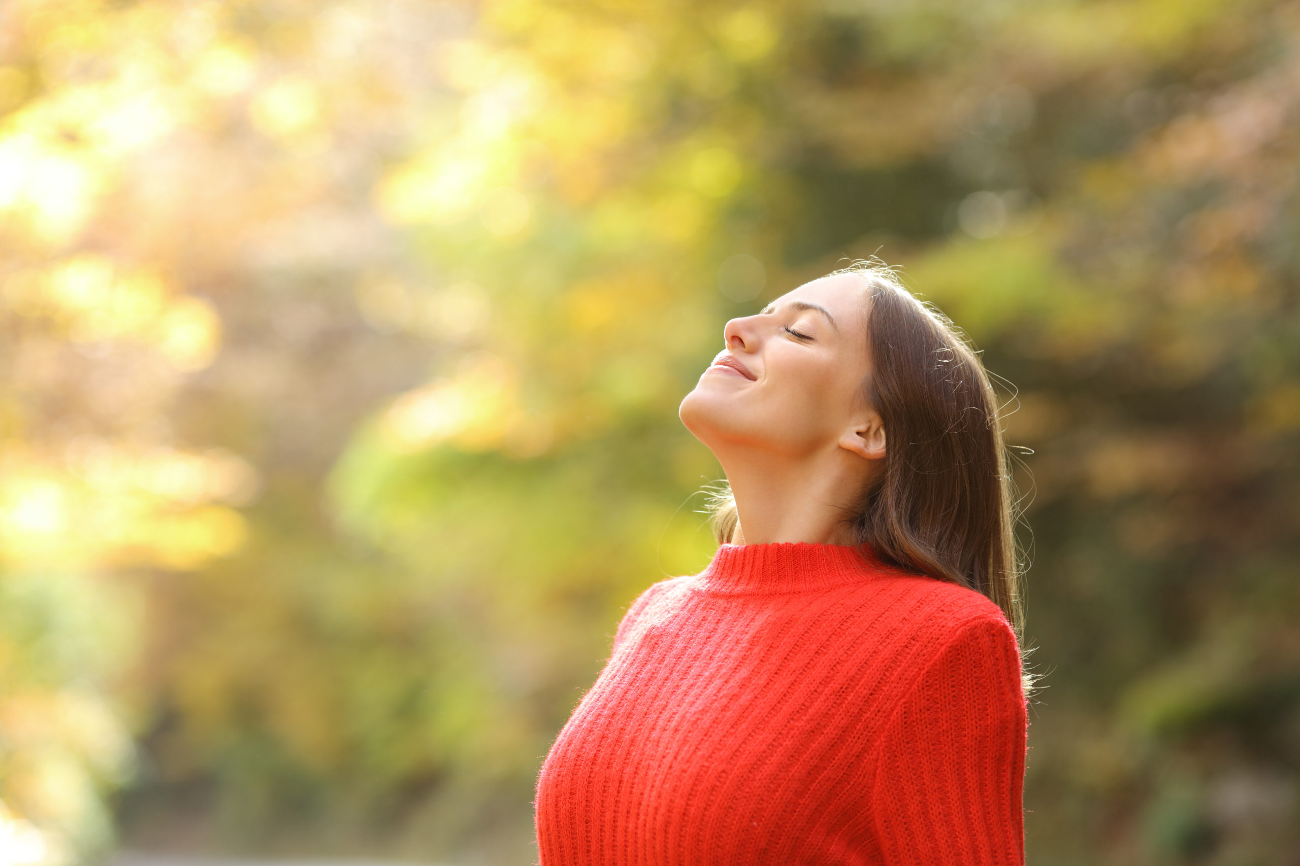 Woman in red breathing fresh air in autumn in a forest