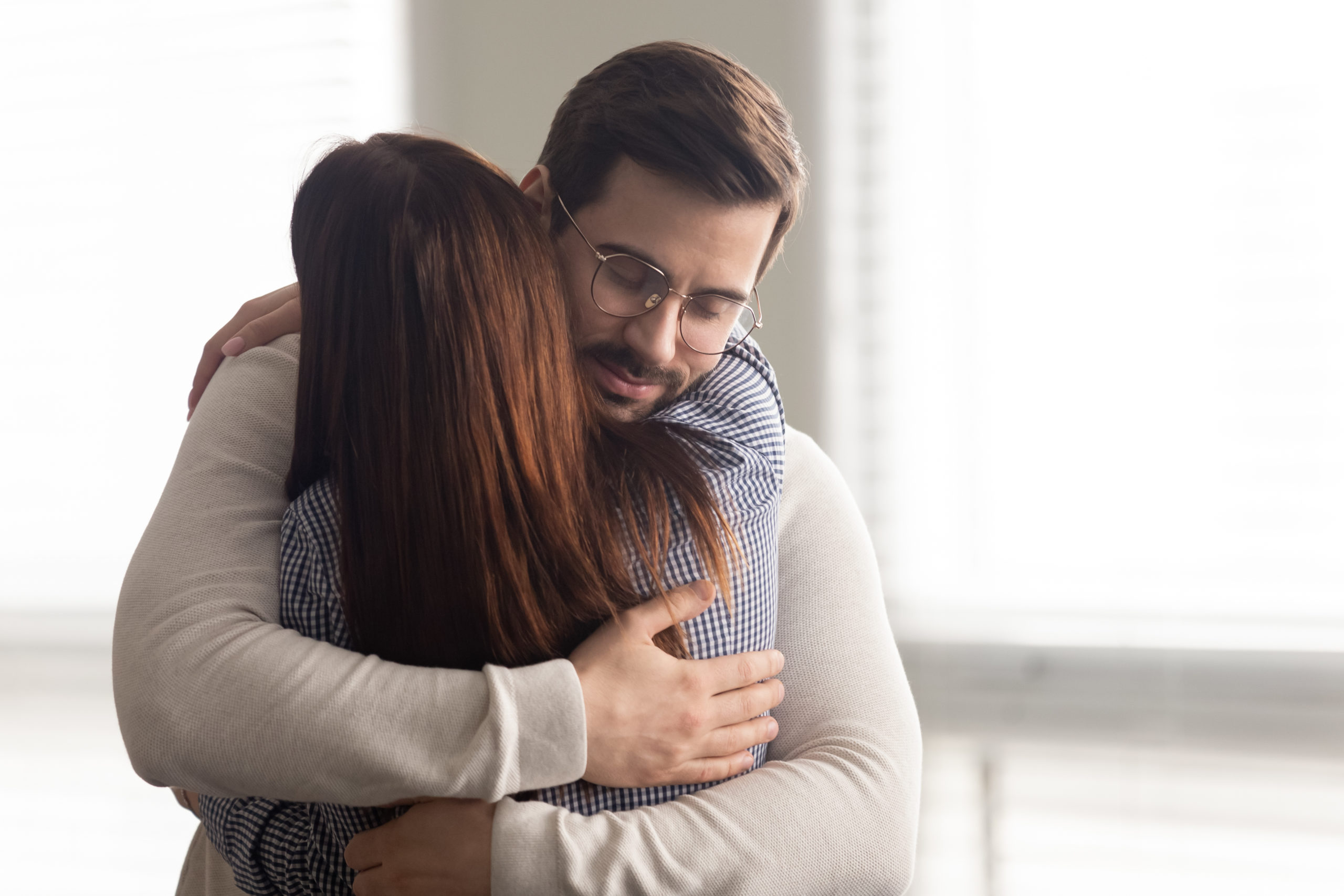 Handsome man embracing woman calms in difficult moment. Husband hugging wife relieves stress from work or health. Friends and couple relationship concept.