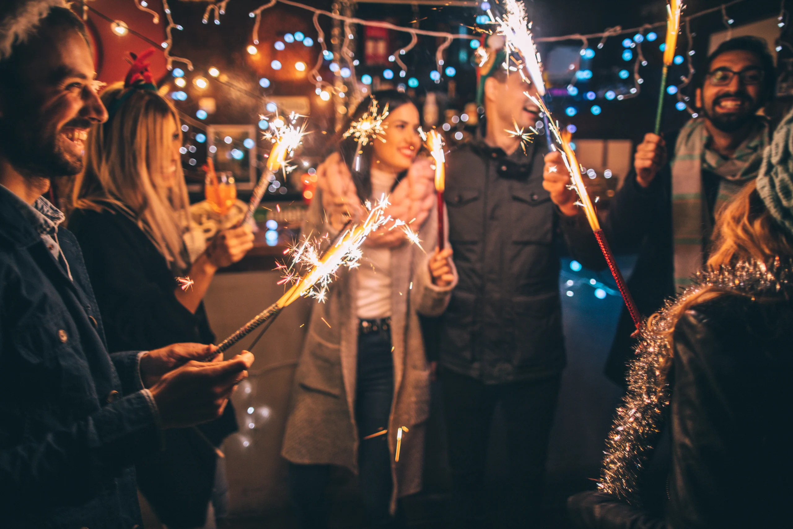 Photo of a cheerful group of friends, at an outdoor New Year's celebration, lightning sparklers at midnight