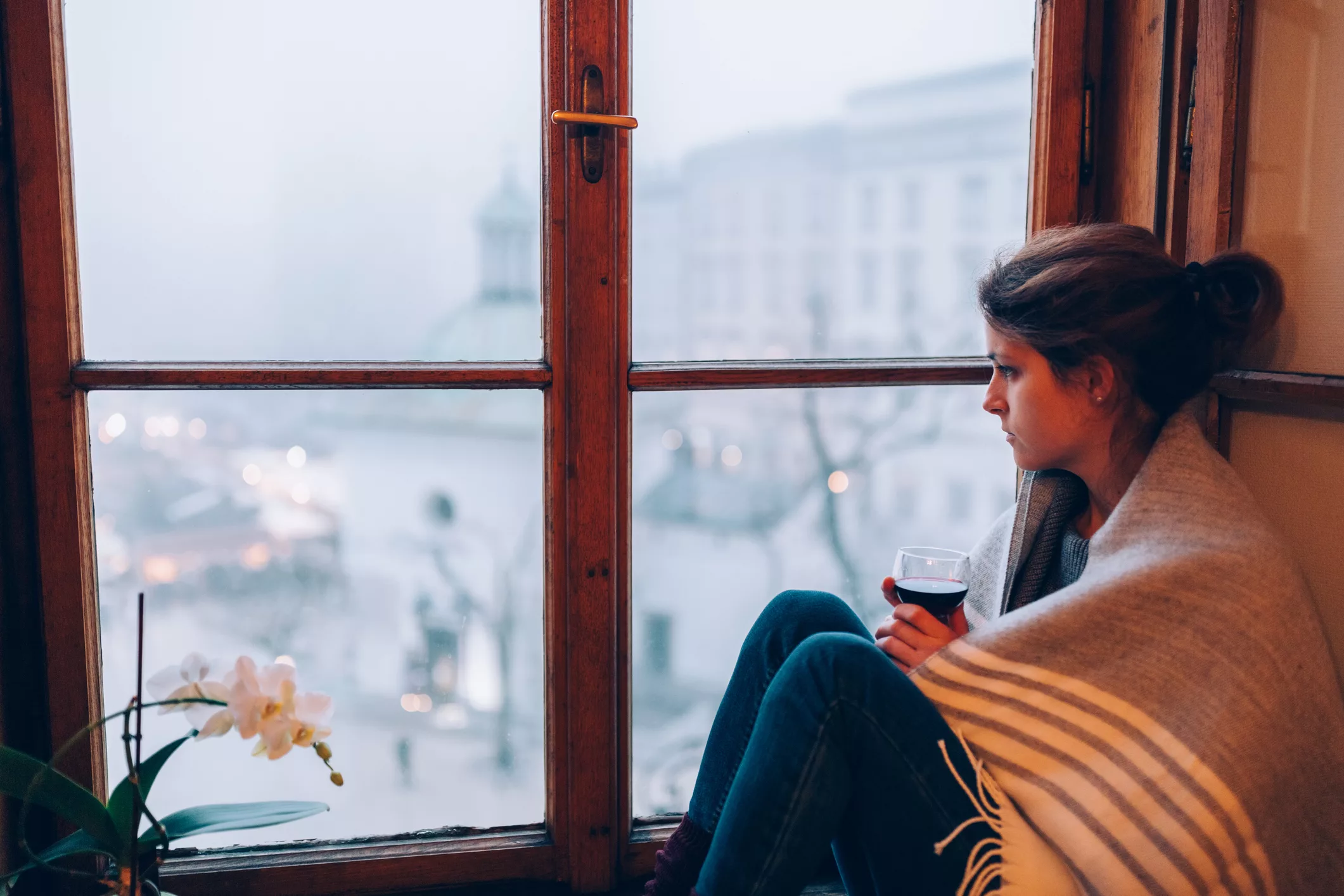Woman with a wine glass looking out the window