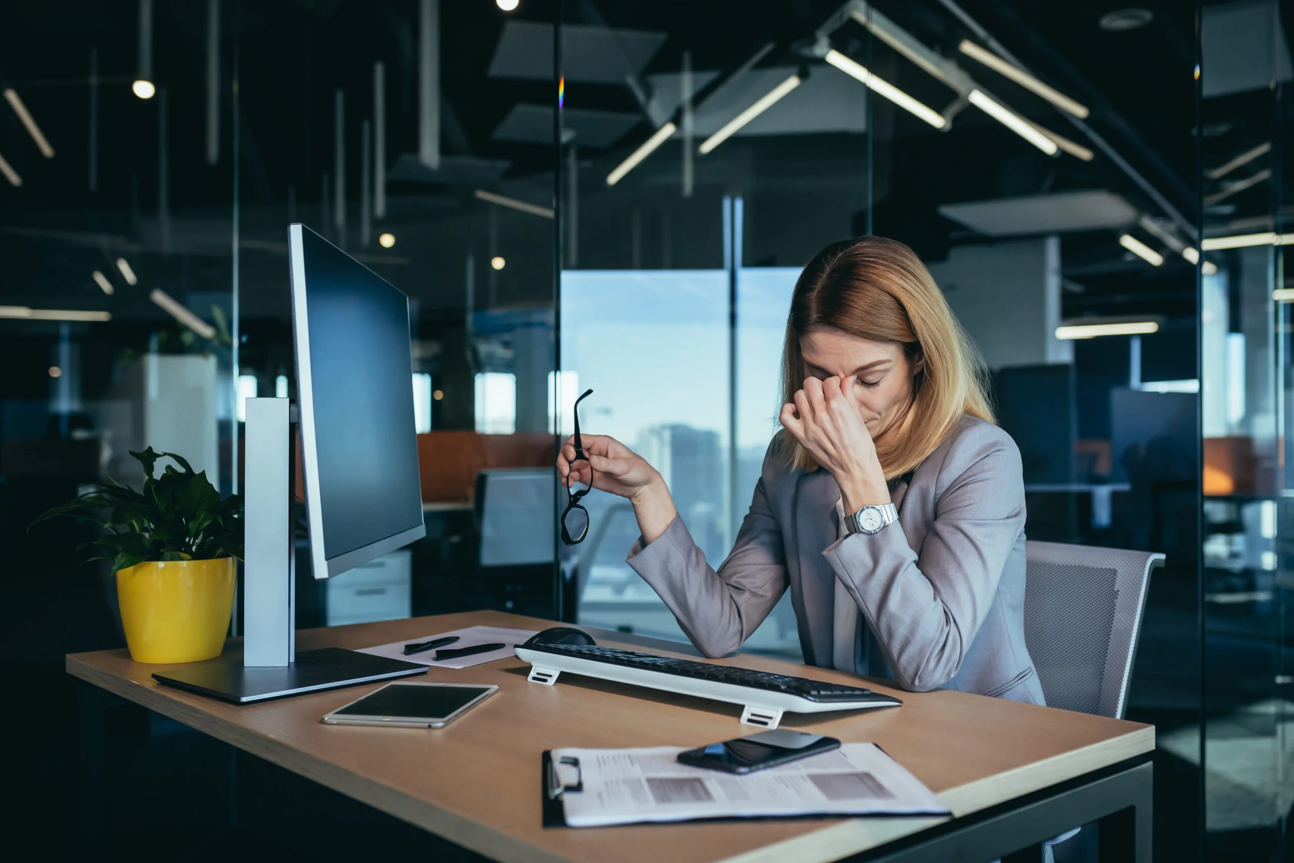 Tired business woman working on computer in modern office, eye pain.