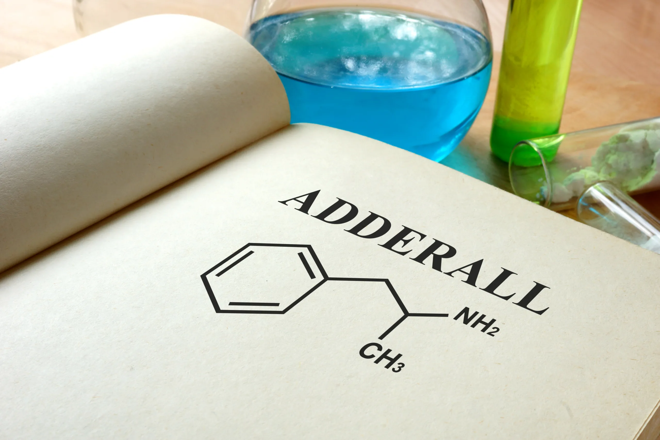 Book with adderall and test tubes on a table.