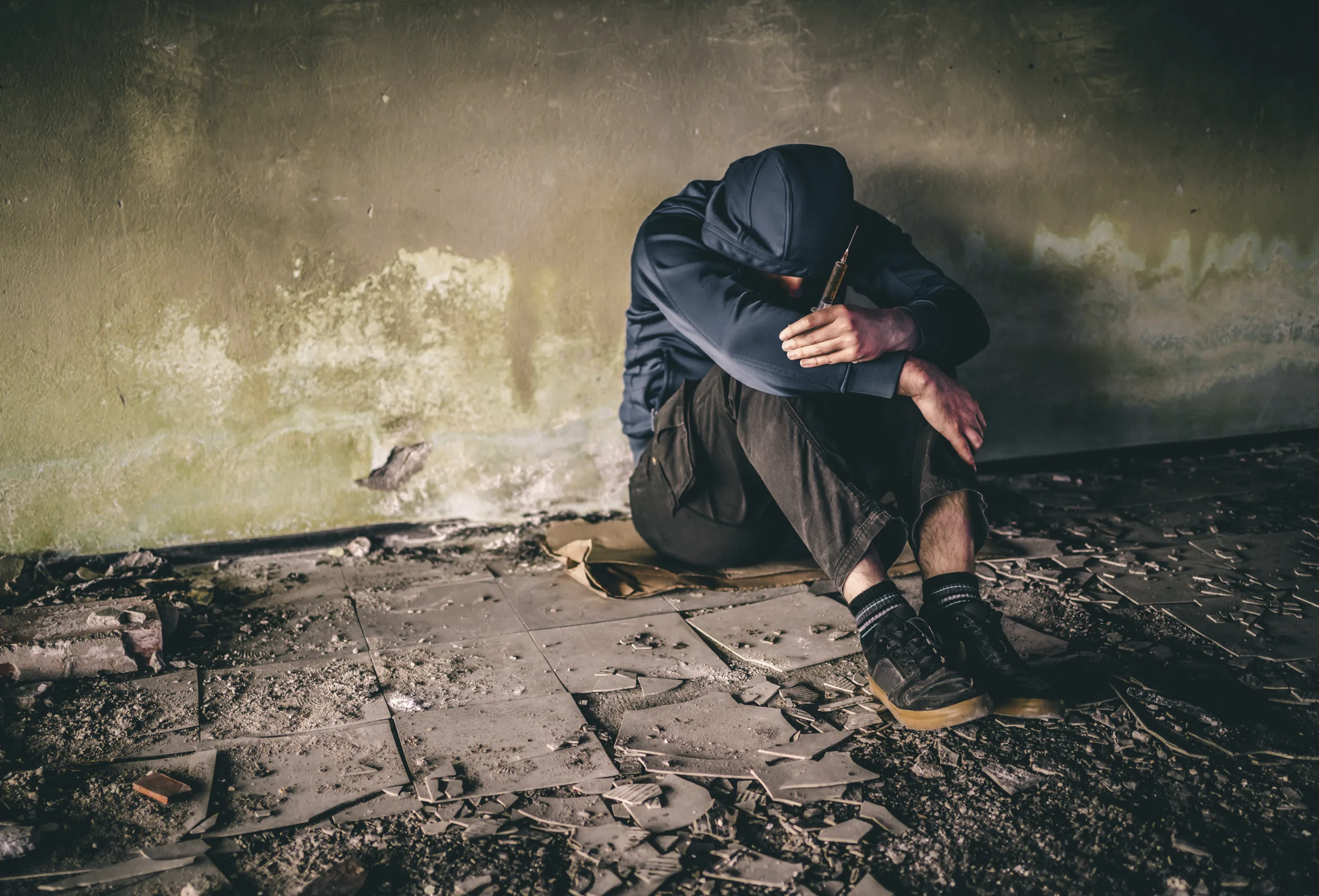 Man drug addict holding syringe with heroin in an abandoned place