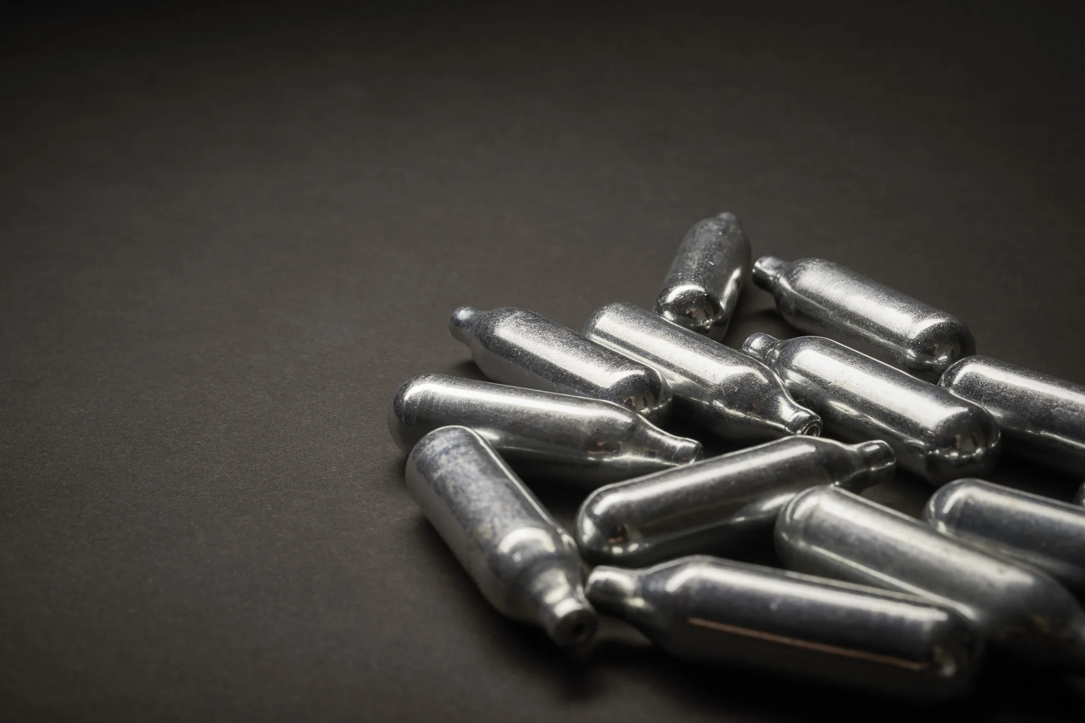 Empty nitrous oxide canisters on a black background