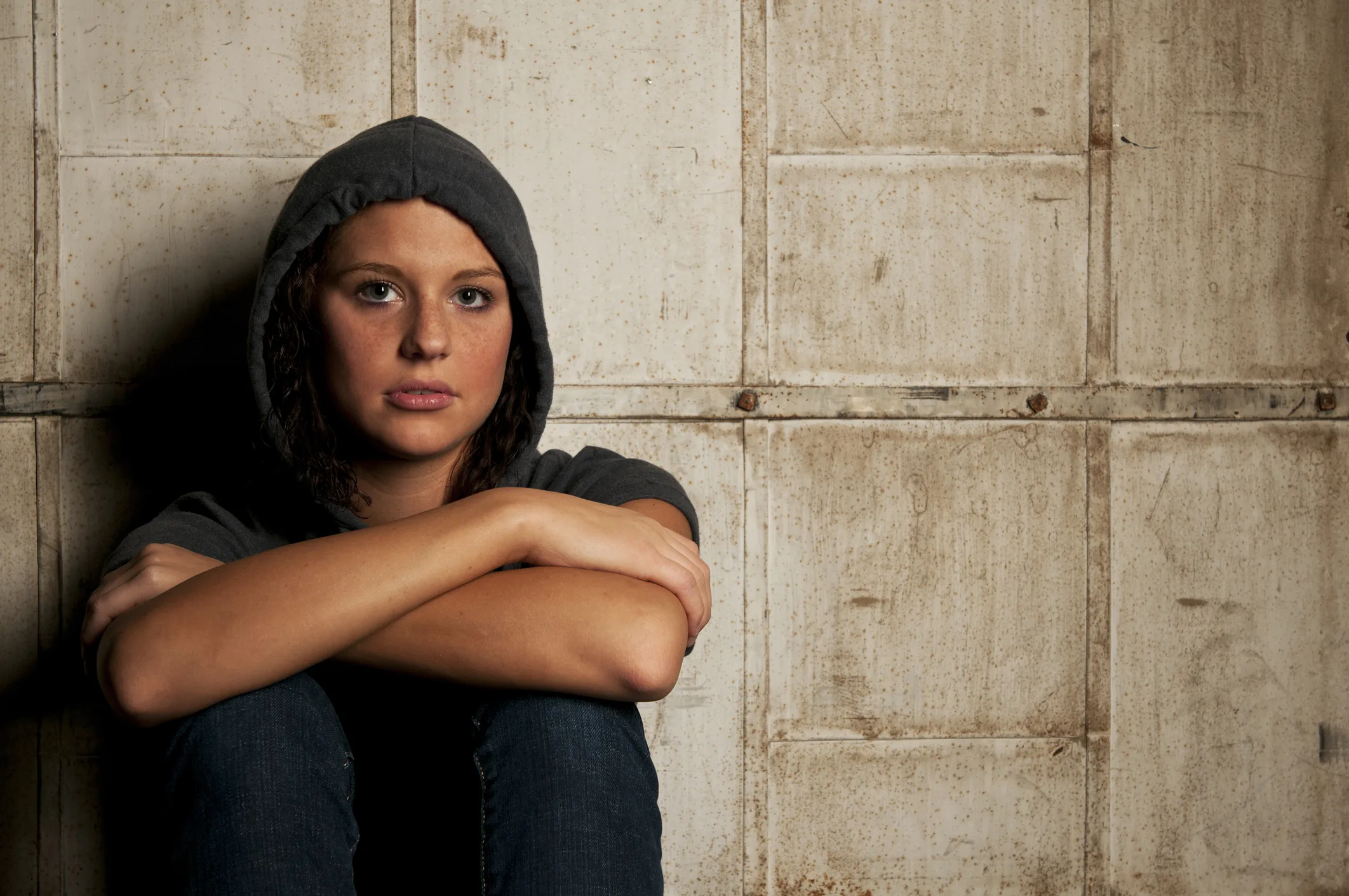 Young female sitting against wall dealing with drug use problems