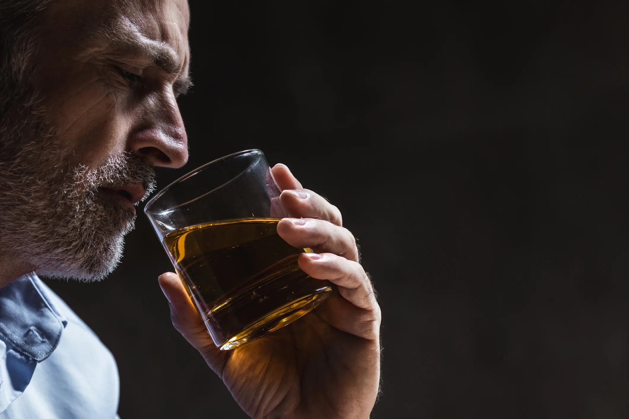 Man contemplating drinking glass of whiskey after being sober