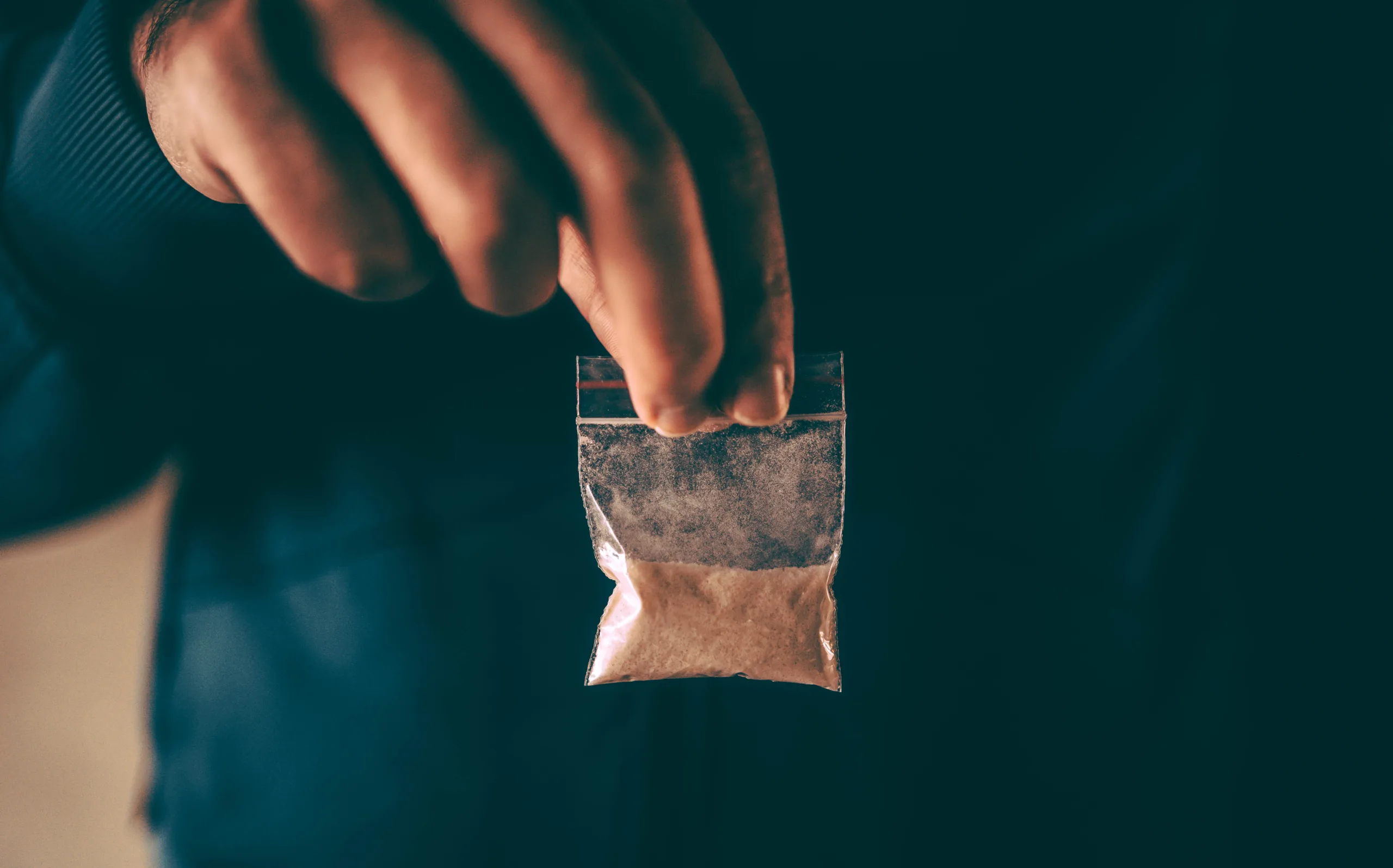 Man holding fish scale cocaine powder in plastic bag