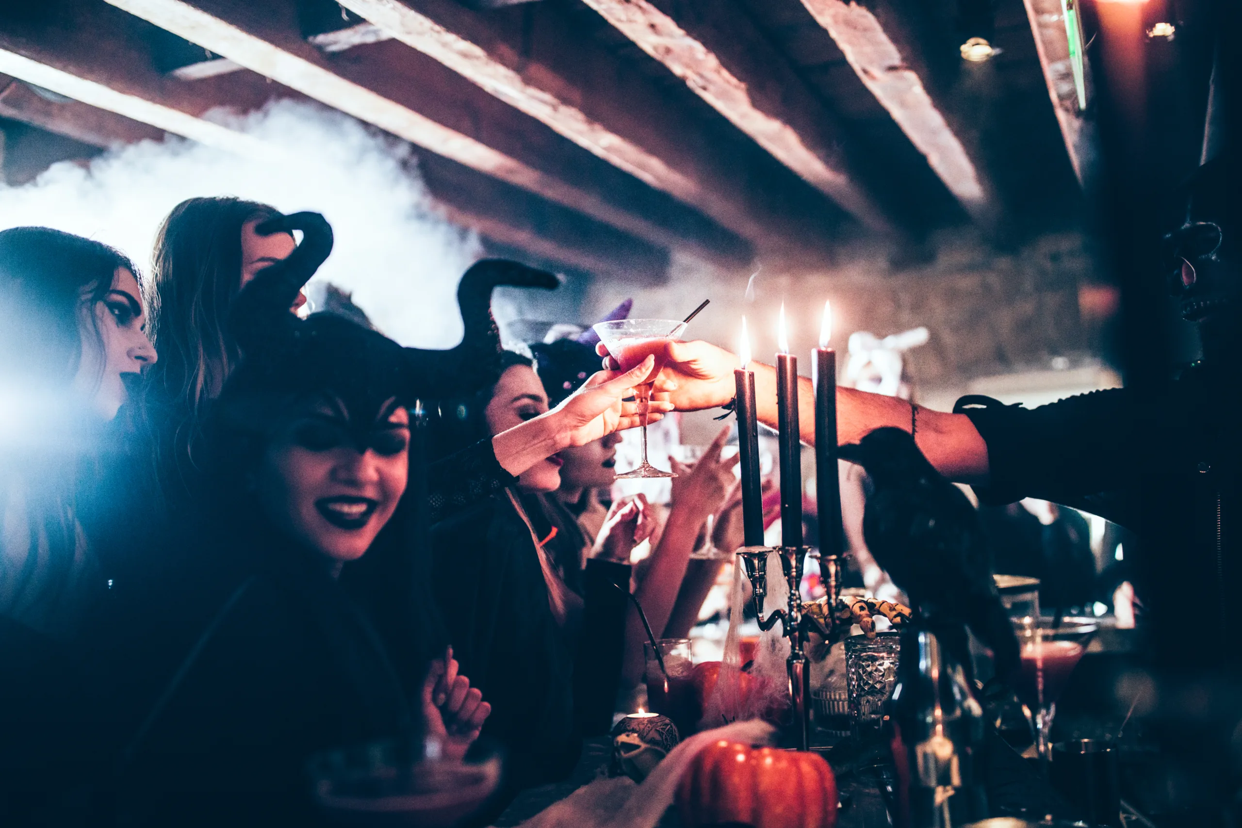 Sober woman working at Halloween nightclub party giving cocktail to woman in scary costume