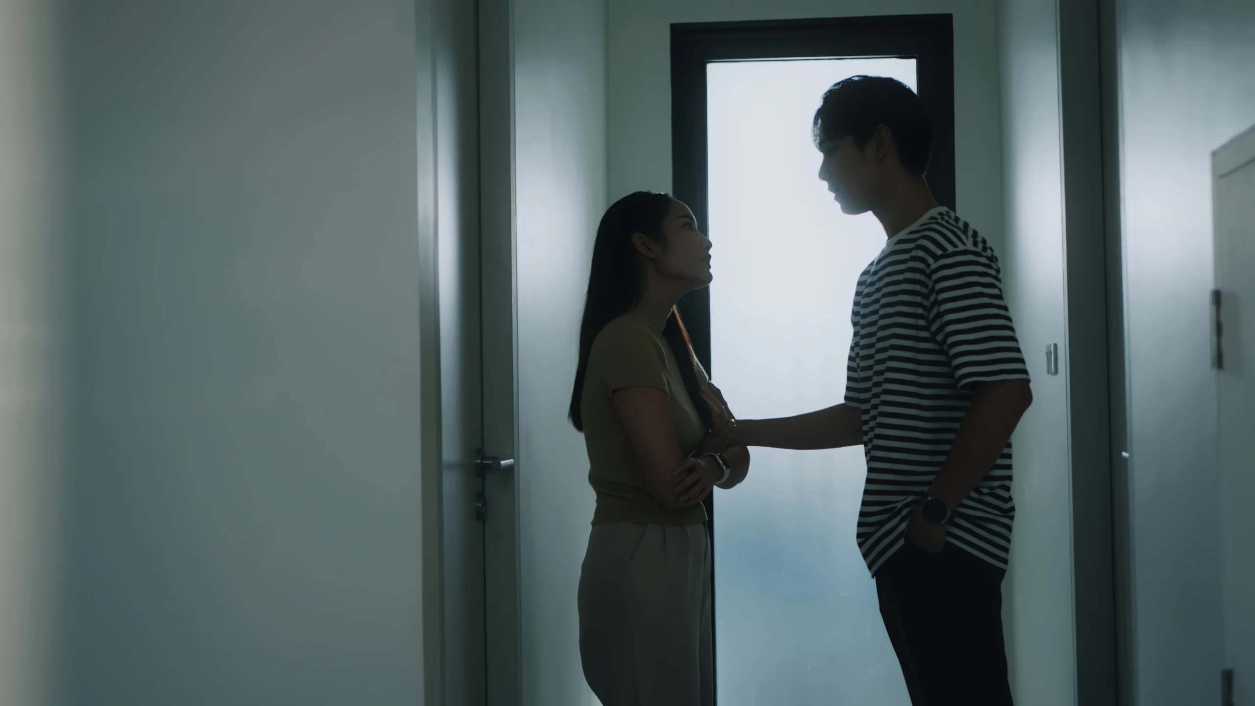 A silhouetted couple engaged in a tense argument in a hallway. A candid and emotional glimpse into relationship struggling with addiction