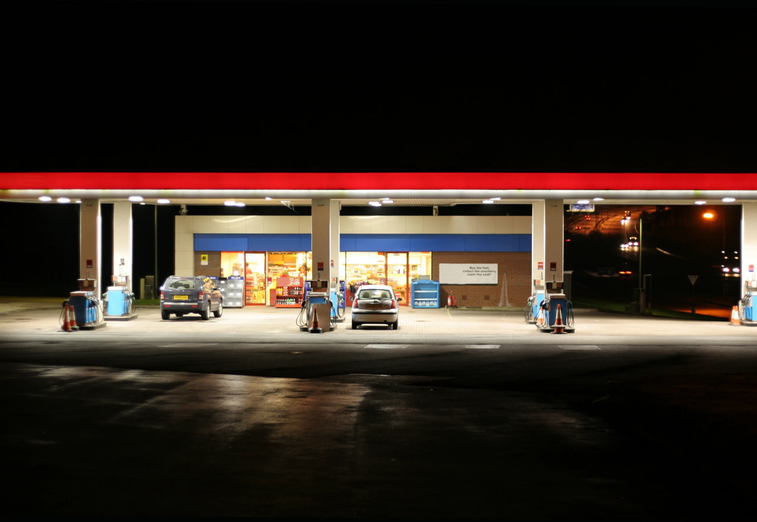 a shot of an all night gas station taken at night with freeway in the background