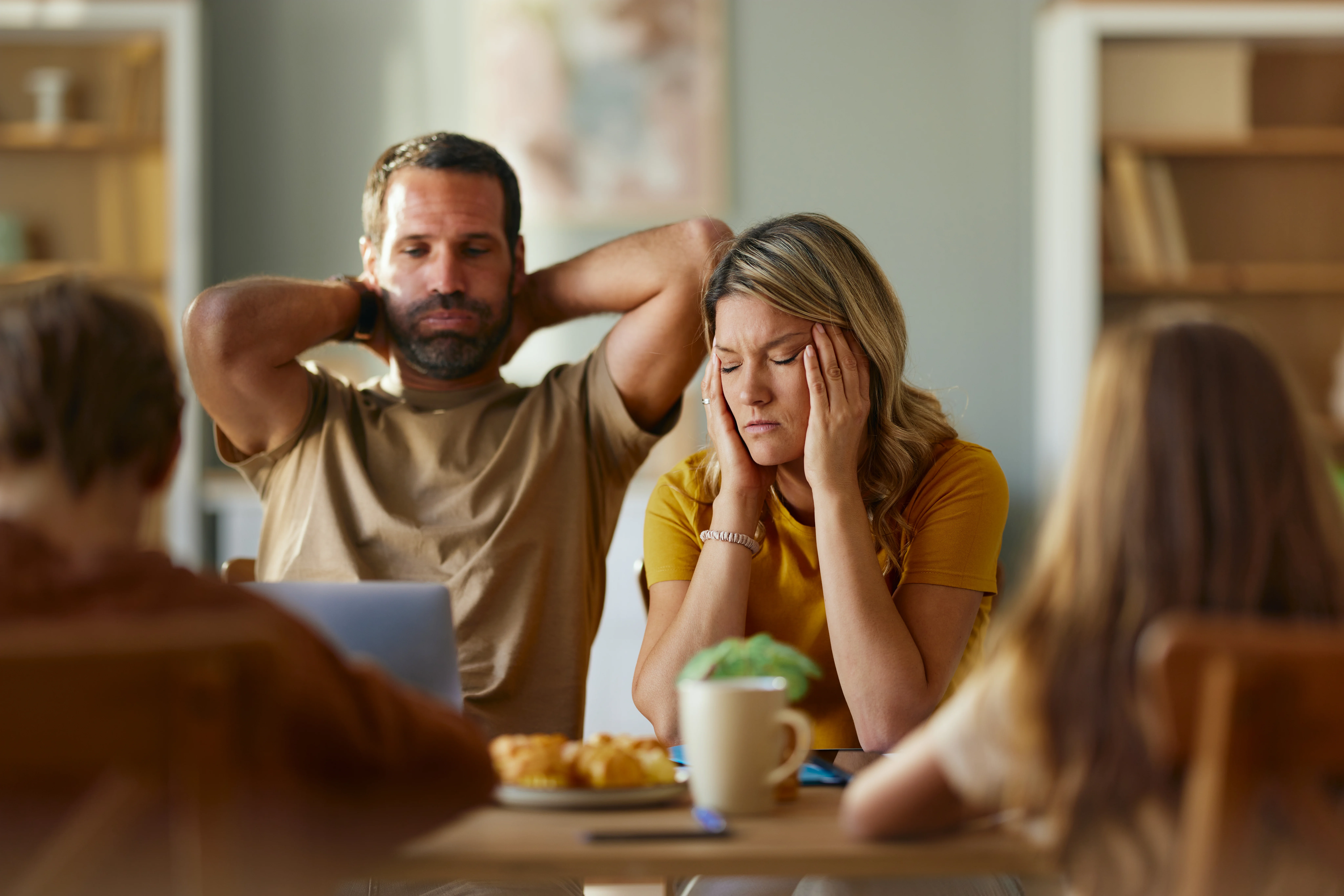Frustrated parents feeling worried while working on a computer at home.